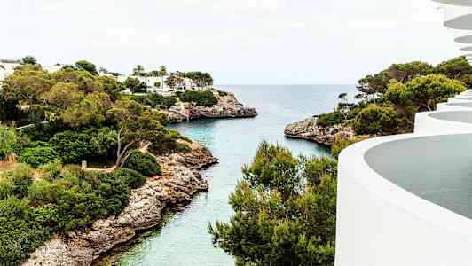 Näkymä lahteen, jossa kirkasta vettä, vihreitä puita ja valkoisia rakennuksia. (Tekoälyn luoma teksti)