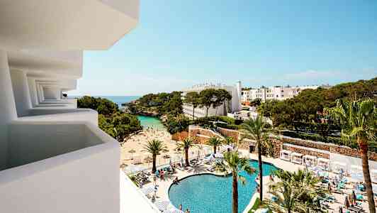 Näkymä parvekkeelta hotellin alueelle, jossa on uima-allas, ranta ja puita. (Tekoälyn luoma teksti)