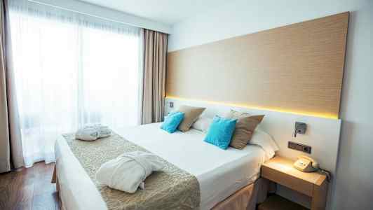 Moderni hotellihuone, jossa on parivuode, kaksi kylpytakkia ja puhelin yöpöydällä. (Tekoälyn luoma teksti)