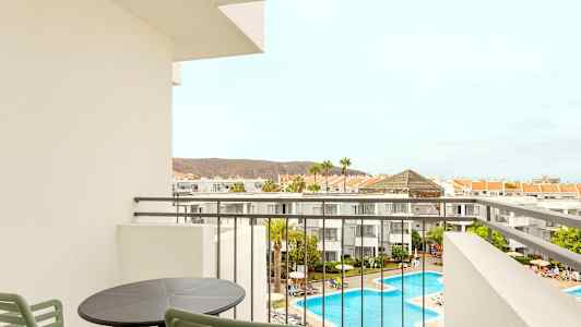 Näkymä parvekkeelta hotellialueelle, jossa on uima-allas ja ympäröiviä rakennuksia. (Tekoälyn luoma teksti)