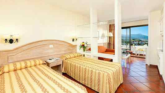 Hotellihuone, jossa kaksi yhden hengen vuodetta, oleskelutila ja parveke. (Tekoälyn luoma teksti)