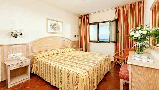 Hotellihuone, jossa on parivuode, yöpöytä ja ikkuna merinäköalalla. (Tekoälyn luoma teksti)