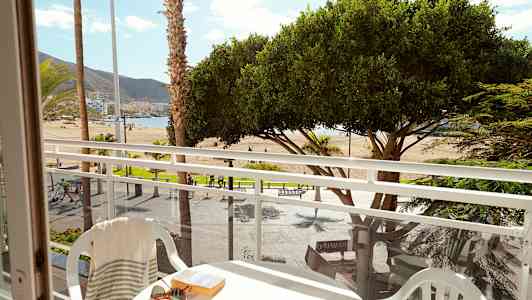 Näkymä parvekkeelta rannalle, jossa on palmuja ja puita. (Tekoälyn luoma teksti)