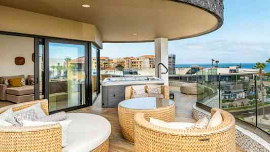 Tilava parveke, jossa istuimet ja poreallas, näkymä rakennuksiin ja merelle. (Tekoälyn luoma teksti)