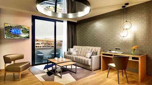 Moderni olohuone, jossa sohva, työpöytä ja näkymä parvekkeelle. (Tekoälyn luoma teksti)