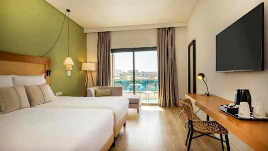 Moderni hotellihuone, jossa ikkuna parvekkeelle ja uima-allasalueelle. (Tekoälyn luoma teksti)