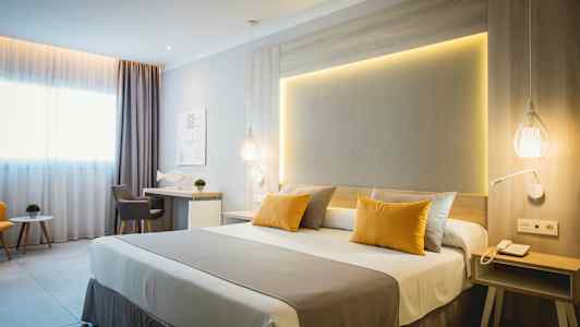 Moderni hotellihuone, jossa on parivuode, kirjoituspöytä ja istuinryhmä. (Tekoälyn luoma teksti)