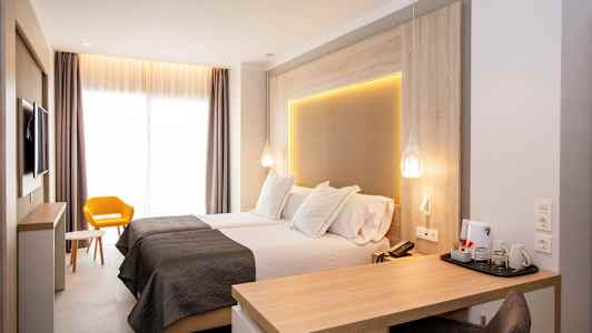 Moderni hotellihuone, jossa on kaksi erillistä vuodetta, kirjoituspöytä ja keltainen tuoli. (Tekoälyn luoma teksti)