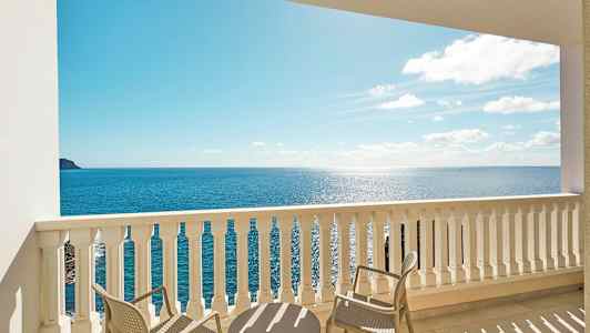 Näköala parvekkeelta, jossa on pöytä ja tuoleja, merelle. (Tekoälyn luoma teksti)