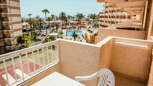 Näkymä parvekkeelta uima-altaalle ja ympäröiviin rakennuksiin aurinkoisella alueella. (Tekoälyn luoma teksti)