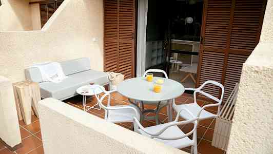 Terassi, jossa harmaa sohva, pyöreä pöytä ja tuoleja. (Tekoälyn luoma teksti)