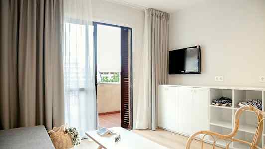 Modernisti sisustettu hotellihuone, jossa avoinna oleva parvekkeen ovi. (Tekoälyn luoma teksti)