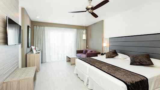 Kuva hotellihuoneesta, jossa on sänky, sohva ja televisio. (Tekoälyn luoma teksti)