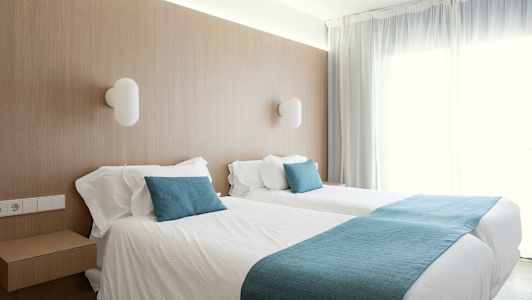 Huone kahdella yksittäisvuoteella ja pehmeillä sinisillä yksityiskohdilla. (Tekoälyn luoma teksti)