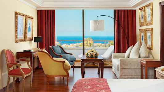 Huone, jossa punaiset verhot, huonekalut ja näkymä merelle. (Tekoälyn luoma teksti)