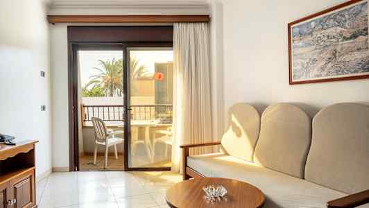 Hotellihuone, jossa sohva, sivupöytä ja parveke näkymällä. (Tekoälyn luoma teksti)