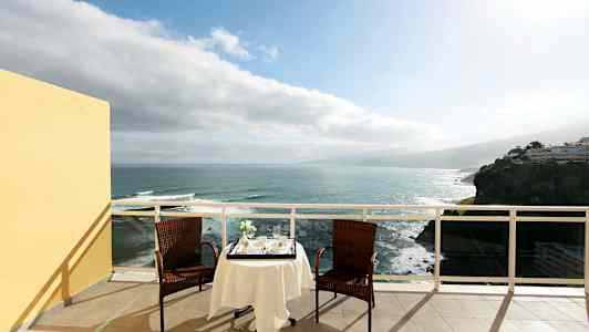 Kaksi tuolia ja pöytä liinalla ovat terassilla, josta on näkymä merelle. (Tekoälyn luoma teksti)