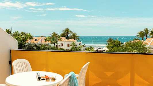 Näkymä parvekkeelta merelle, aurinkotuoleja ja viheralueita. (Tekoälyn luoma teksti)