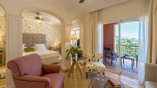 Hotellihuone, jossa on oleskelualue, sänky ja parveke. (Tekoälyn luoma teksti)