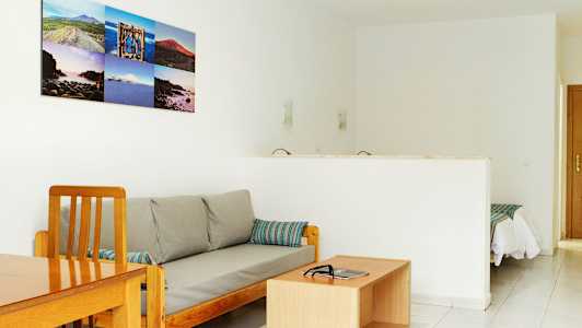 Olohuone, jossa sohva ja sohvapöytä sekä aukko makuuhuoneeseen. (Tekoälyn luoma teksti)