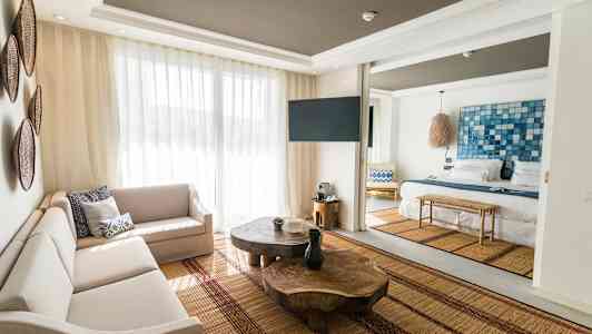 Kuva valoisan ja modernin hotellihuoneen olohuonekalusteista ja sängystä. (Tekoälyn luoma teksti)