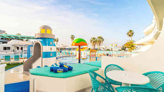 Uima-allas aurinkotuoleilla ja leikkialue vesileluilla, mukaan lukien värikäs majakan muotoinen liukumäki. (Tekoälyn luoma teksti)