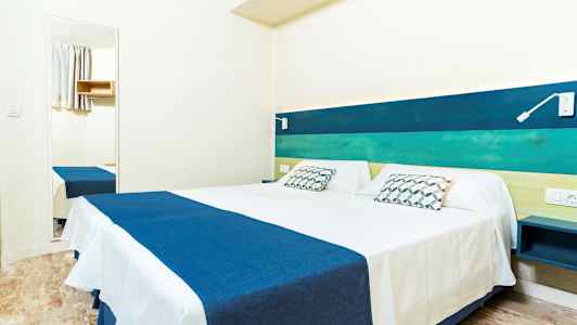 Kahden hengen huone, jossa sänky sinisillä ja valkoisilla vuodevaatteilla, pääty sinivihreissä sävyissä sekä seinäpeili. (Tekoälyn luoma teksti)