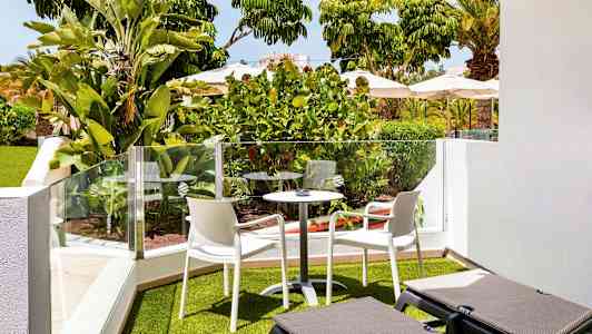 Puutarhaterassi, jossa viherkasveja, ulkokalusteita ja aurinkotuoleja. (Tekoälyn luoma teksti)