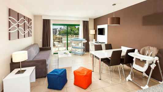 Moderni olohuone, jossa sohva, ruokapöytä, lastenistuin ja näkymä parvekkeelle. (Tekoälyn luoma teksti)