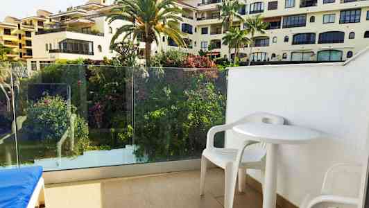 Näkymä parvekkeelta, jossa on valkoisia muovikalusteita ja ympärillä vehreää kasvustoa. (Tekoälyn luoma teksti)