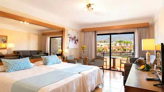 Hotellihuone, jossa on kaksi sänkyä, oleskelutila ja parveke näköalalla. (Tekoälyn luoma teksti)