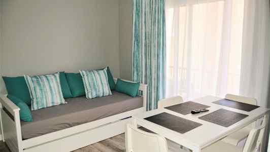 Olohuone valkoisella sohvasängyllä ja neljällä tuolilla varustetulla ruokapöydällä. (Tekoälyn luoma teksti)