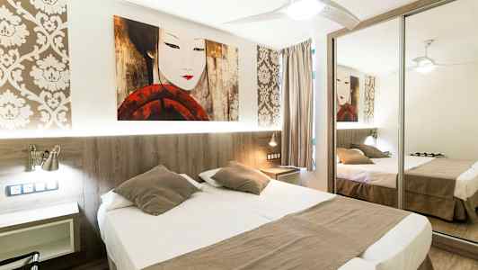 Hotellihuone, jossa on parivuode, peilikaappi ja koristeellinen tapetti. (Tekoälyn luoma teksti)