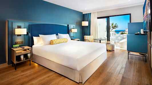 Hotellihuone, jossa on parisänky, istuinkalusteita ja näkymä merelle. (Tekoälyn luoma teksti)