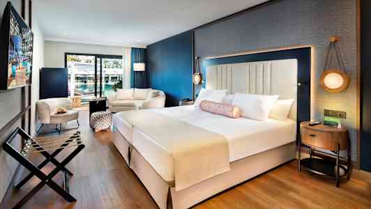 Nykyaikainen hotellihuone, jossa parivuode, istuinalue ja parveke. (Tekoälyn luoma teksti)