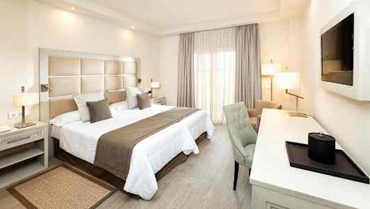 Hotellihuone, jossa on parivuode, kirjoituspöytä ja tuoli. (Tekoälyn luoma teksti)