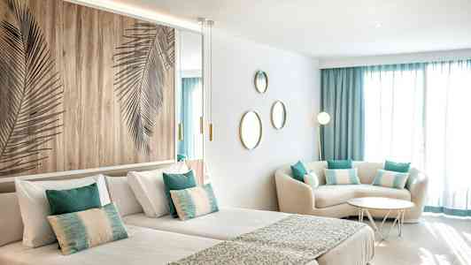 Moderni hotellihuone, jossa kaksi yhden hengen sänkyä, istuinryhmä ja koristeita. (Tekoälyn luoma teksti)