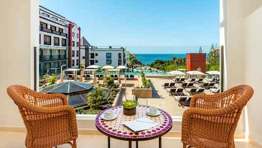 Näkymä parvekkeelta hotellin uima-altaalle, jossa on aurinkotuoleja, ja taustalla meri. (Tekoälyn luoma teksti)