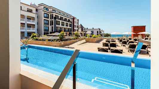 Näkymä uima-altaalle, jossa on aurinkotuoleja, hotellien ympäröimänä. (Tekoälyn luoma teksti)