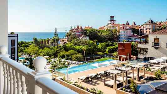 Näkymä parvekkeelta hotellialueelle, jossa on uima-allas ja puutarha sekä meri taustalla. (Tekoälyn luoma teksti)