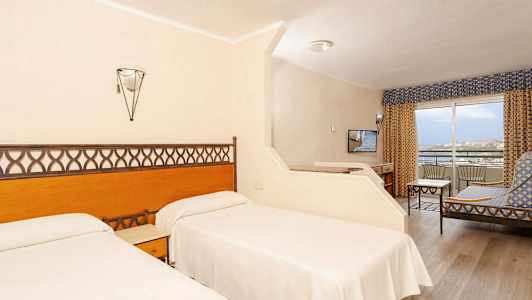 Hotellihuone, jossa on kaksi yhden hengen vuodetta, oleskelutila ja parveke. (Tekoälyn luoma teksti)