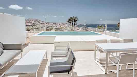 Terassi, jossa on huonekaluja, näkymä uima-altaalle ja taustalla meri. (Tekoälyn luoma teksti)