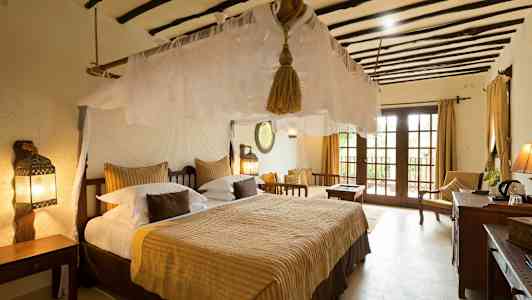 Makuuhuone, jossa suuri sänky, hyttysverkko ja perinteisiä huonekaluja. Ikkunat näkymällä. (Tekoälyn luoma teksti)