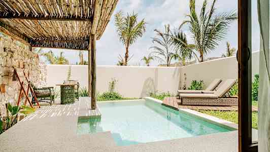 Terassi, jossa pieni uima-allas, aurinkotuoleja ja kasvillisuutta puusäleikön alla. (Tekoälyn luoma teksti)