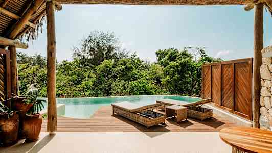 Infinity-allas, jossa on puuterassi ja aurinkotuoleja trooppisessa ympäristössä. (Tekoälyn luoma teksti)