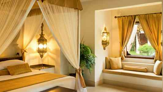 Tyylikäs makuuhuoneen sisustus, jossa on katosvuode ja ikkunanpääty kultatyynyillä. (Tekoälyn luoma teksti)