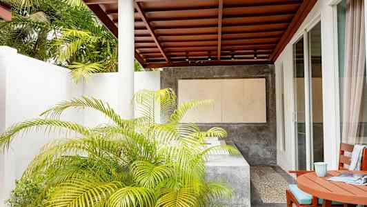 Terassi, jossa on katto, pöytä ja tuolit, sekä kasveja ja nykyaikainen ympäristö. (Tekoälyn luoma teksti)