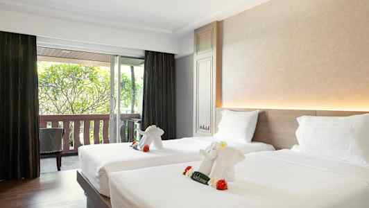 Hotellihuone, jossa on kaksi sänkyä koristeltuna pyyhe-eläimillä, jotka muistuttavat pieniä norsuja. (Tekoälyn luoma teksti)