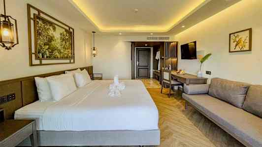 Modernisti sisustettu hotellihuone, jossa on parivuode, sohva ja työtila. (Tekoälyn luoma teksti)