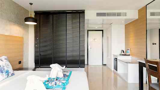 Hotellihuone, jossa sänky, koristeltu elefantin muotoisilla pyyhkeillä, sekä työtila. (Tekoälyn luoma teksti)